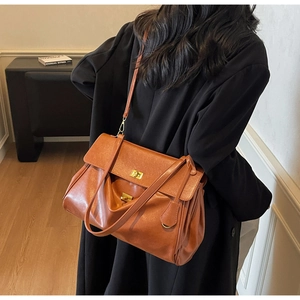 Brown leather tote bag featuring a metallic turn-lock closure and slim shoulder strap