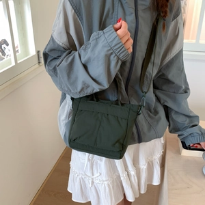 Detail of dark green canvas tote bag with front pockets and military green shoulder strap