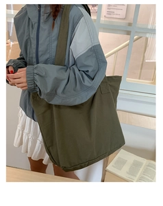 Grand sac fourre-tout en toile vert olive porté à l'épaule en mode lifestyle