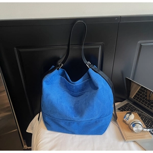 Gros plan du sac fourre-tout en daim bleu vif avec bandoulière en cuir noir chic