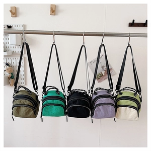 Detail of five mini nylon crossbody bags in various colors with double zip compartments