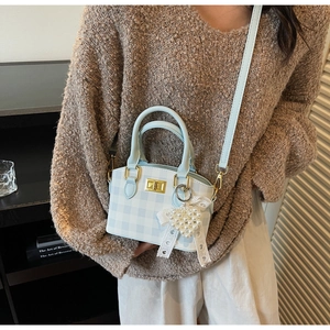 Detailed view of light blue checkered mini handbag with pearl heart charm on a model