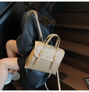 Detail of khaki leather backpack with flap closure and metal buckle on wooden stairs