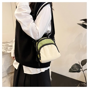 Detail of minimalist green and cream canvas crossbody bag with double zipper