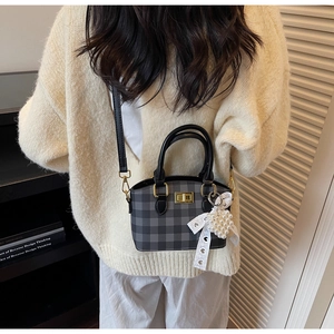Close-up of checkerboard crossbody bag with lace bow and pearl heart pendant charm