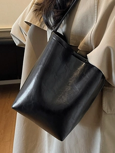 Grand sac cabas noir en cuir sur mannequin portant un trench-coat d'automne élégant