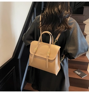 Detail of light brown matte leather backpack with gold buckles and dual strap design