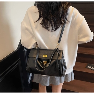 Detail of the golden rotary lock and matte black leather texture on a large capacity bag