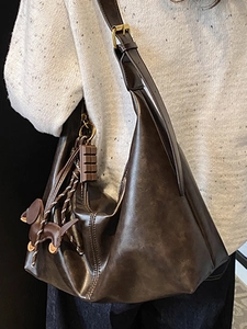 Deep brown oversized hobo bag in premium PU leather with cute pendants on a model
