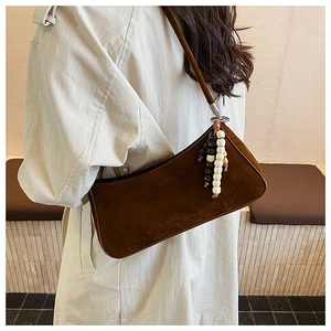 Brown faux suede shoulder bag with wood bead charm detail shown on model's shoulder