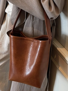 Grand sac cabas marron minimaliste en cuir ciré porté par un mannequin pour le quotidien