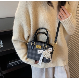 Detail of grey plaid handbag with white lace bow and pearl heart charm accessories