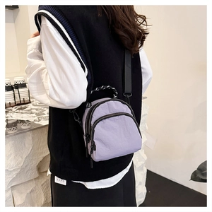 Detail of the purple nylon mini shell bag featuring dual zipper and woven strap on model
