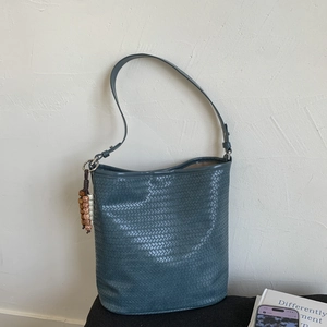 Detailed view of dark grey-blue woven bucket bag with unique beaded charms and fine texture