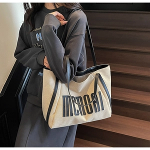 Détail du sac cabas en toile beige avec finitions en cuir noir et logo MERORI