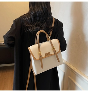 Close-up of structured white tote bag with brown leather trim and fashion lettering