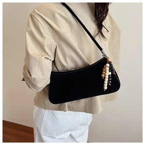 Close-up of black retro shoulder bag with wooden bead charms on a model for work