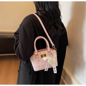 Detail of pink plaid handbag with pearl heart charm and lace bow on black blazer