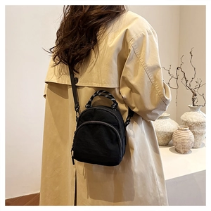 Rear view of model wearing a black canvas mini backpack with striped handles and slim straps