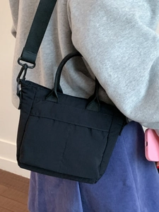 Mini black nylon tote bag with wide shoulder strap shown on a model for daily styling