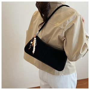 Close-up of black retro underarm bag with decorative beaded tassel on the side