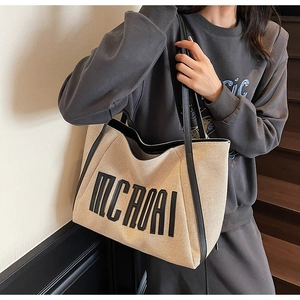 Détail d'un grand sac cabas en toile avec bordure noire et lettrage MCROAI à l'épaule