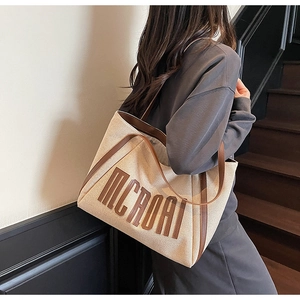 Détail du sac cabas en toile avec garniture en cuir marron et logo MCROAI tendance