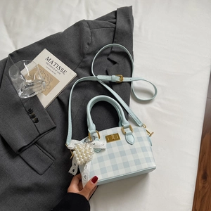 Close-up of blue and white checkered bag with pearl heart charm and lace bow detail