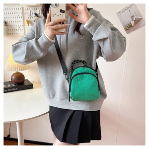 Detail view of mini bright green nylon crossbody bag with adjustable black shoulder strap
