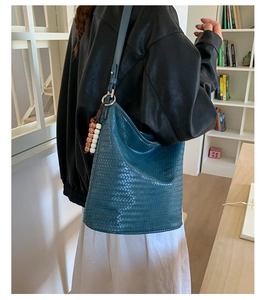 Detail of teal woven leather hobo bag with bohemian beaded charm and silver hardware