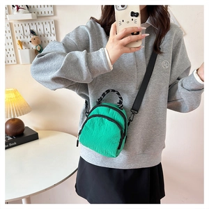 Detail of green nylon mini crossbody bag with double zippers and black strap