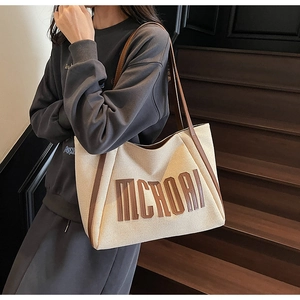 Détail du sac fourre-tout en toile avec poignées en cuir marron et patch logo MCROAI