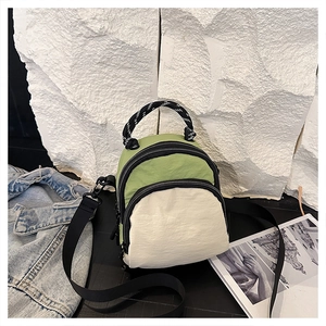 Detail of multi-functional green and beige mini backpack with adjustable strap and woven handle