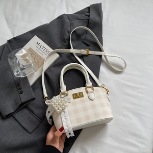 Detail of checkered shell handbag with pearl heart charm and lace bow decoration