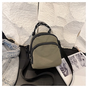 Detail of olive green nylon bag with dual zipper compartments and striped rope handle