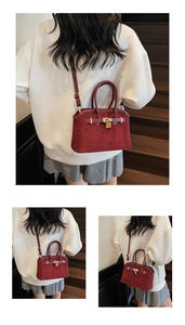 Détail d'un sac cabas bordeaux en daim avec fermoir doré et accents de lanières en cuir