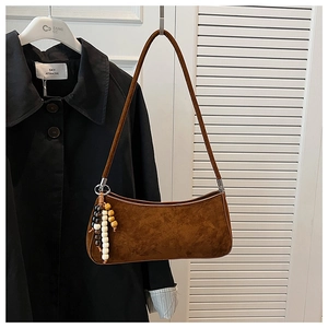 Detailed view of dark brown suede underarm bag with decorative wooden beads and slim strap