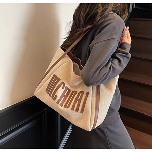 Sac fourre-tout en toile avec finitions en cuir porté par un modèle pour le quotidien