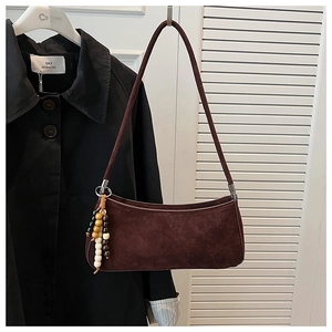 Detail of dark brown faux suede baguette bag with wooden beaded tassel accessory