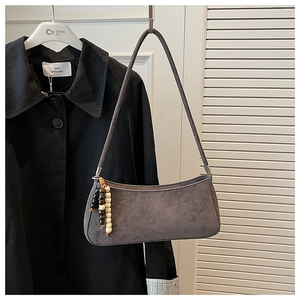 Grey suede baguette bag with colorful wooden beads hanging on a minimalist hanger
