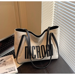 Détail du sac fourre-tout en toile montrant la texture, les anses et l'imprimé chic