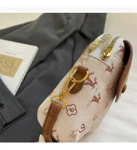 Détail des garnitures dorées et de la bandoulière brune sur le petit sac à motif