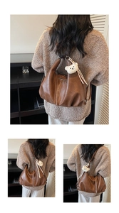 Detailed macro view of vintage brown leather tote bag with soft texture and plush bear charm