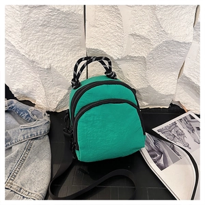 Detail view of emerald green nylon shell bag with multi-layer zippers and braided handle