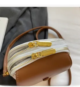 Gros plan détaillé des doubles fermetures éclair dorées sur un sac bandoulière marron chic