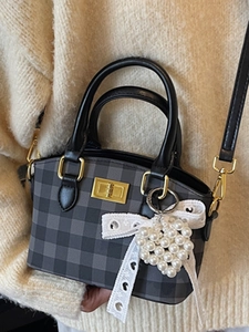 Retro checkered handbag with golden clasp and heart charm, shown in a cozy aesthetic setting