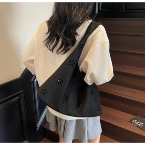 Détails des motifs de fleurs ajourés au laser sur un sac à main noir en daim mat