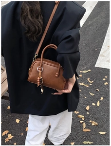 Détail du sac Boston en cuir marron avec breloque en bois et bandoulière réglable