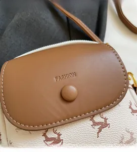 Détail d'un petit sac bandoulière avec rabat en cuir marron et motif de rennes