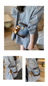 Detail of vintage denim bucket bag featuring leather trim, gold buckle and teddy bear charm